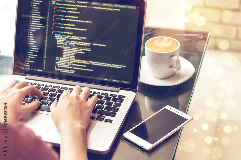 A programmer typing source codes in a coffee shop with a relaxing working environment. Studying, Working, Technology, Freelance Work, Web Design Business, and Web Development Concept.