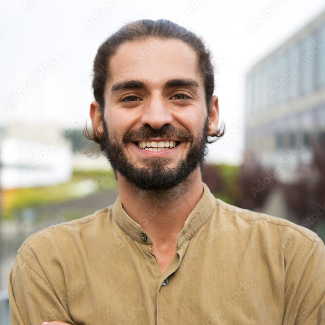 Handsome happy bearded man. Portrait of cheerful young man standing outdoors and smiling at camera. Emotion concept